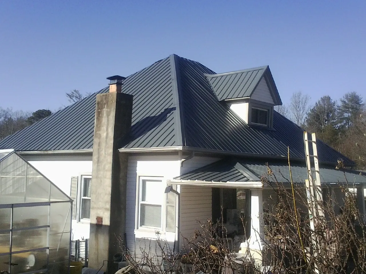Dark blue standing seam metal roof on a white farmhouse with dormer — Slate & Tile Roof Repair by Roofing Brothers in Peru
