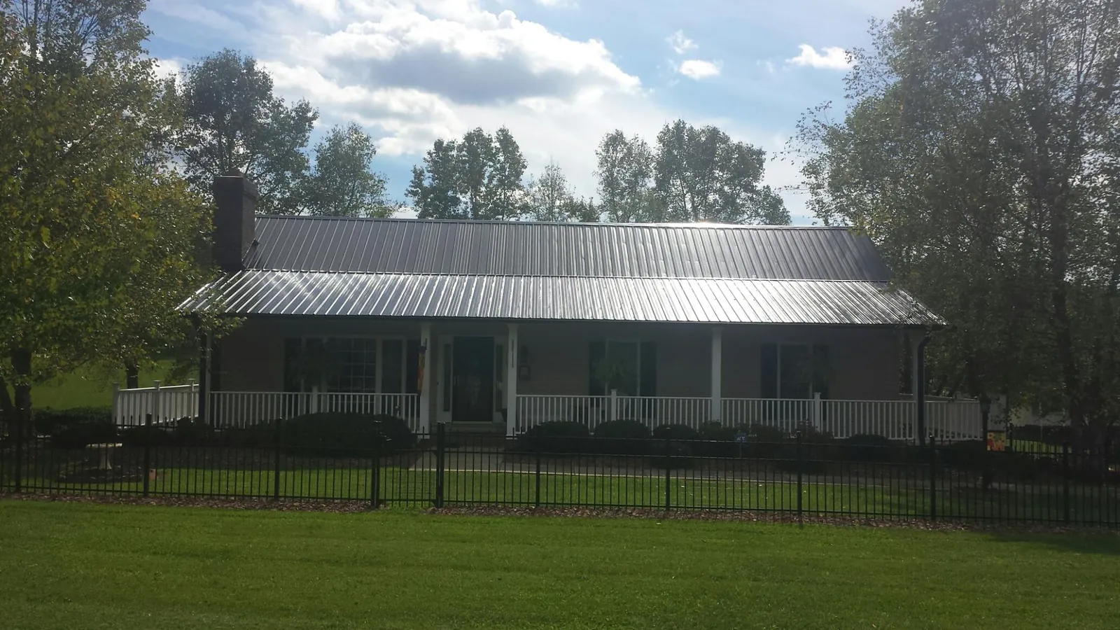 Gray metal roof on a brick ranch with a full width front porch — Gutter Guard Installation work by our crew in Peru