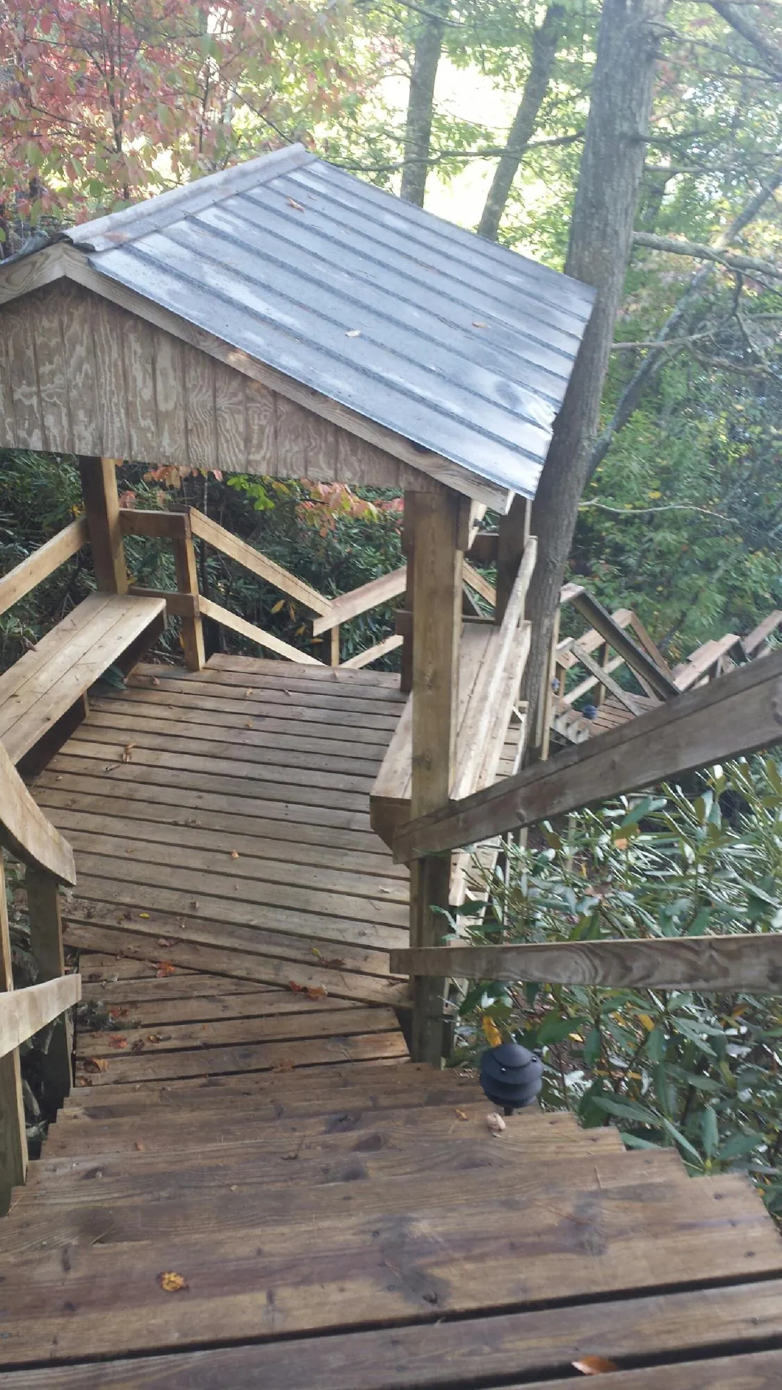 Metal roofed shelter over wooden steps on a wooded walkway — Skylight Repair & Installation work by our crew in Peru